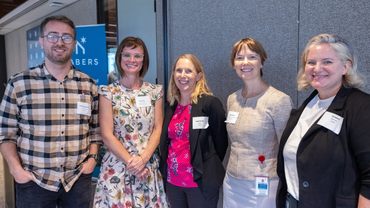 5 people stand smiling at the conference