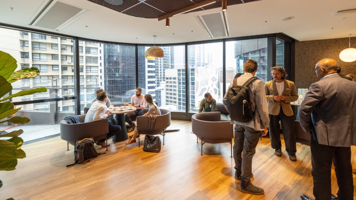 A gathering of people sitting and standing and talking to each other