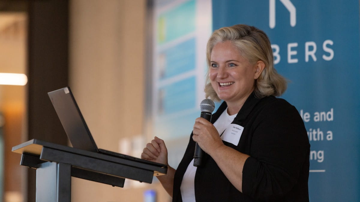 A closeup image of a woman holding a microphone and smiling